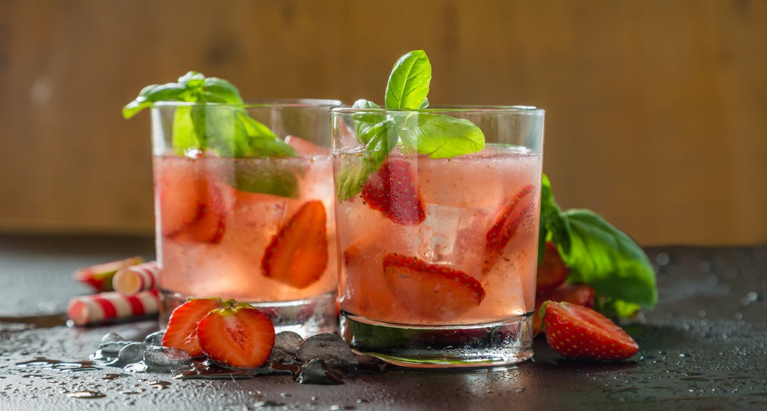 Dos vasos de bebida fría hecha con té verde con frutos rojos y hojas de hierbabuena